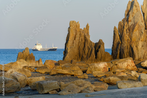 夕陽に照らされる橋杭岩と遠くに浮かぶ船