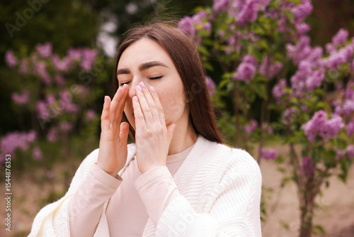 Woman suffering from seasonal pollen allergy near blossoming shrub on spring day