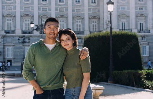 Happy travelers posing for photo near landmark in Madrid, wrapped in warm light and joyful connection. Romance and exploration merge in peaceful cultural backdrop