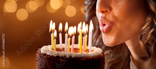 Close-up of an unrecognizable adult woman blowing out the candles on a small chocolate cake celebrating her birthday