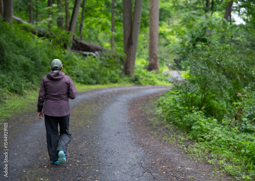 A woman walking alone on a forest road enjoying the serenity and solitude of being in nature