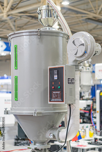 Large industrial mixerprocessor with cylindrical base and two silver tanks, indoors in an industrial setting, artificial lighting, no people, metallic hues, blue components, functional style, side v