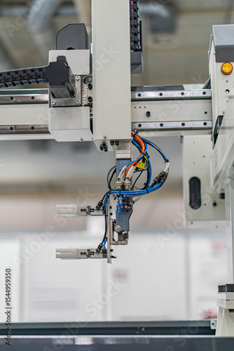 Close-up view of an industrial robot, predominantly white, grey, and black in color, with visible wires and cables No people present Even lighting without harsh shadows Standard photograph style