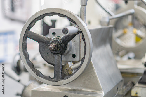 Industrial machine parts, gray and metallic tones, large gear or sprocket, flange, factory or workshop setting, mechanical structure, muted colors, no people, no text