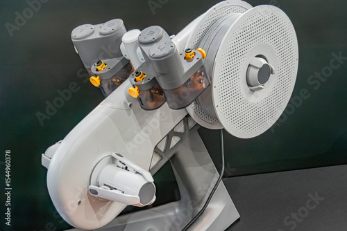 White and black robotic device with central cylinder, yellow figurines, indoor setting, technical exhibit or convention