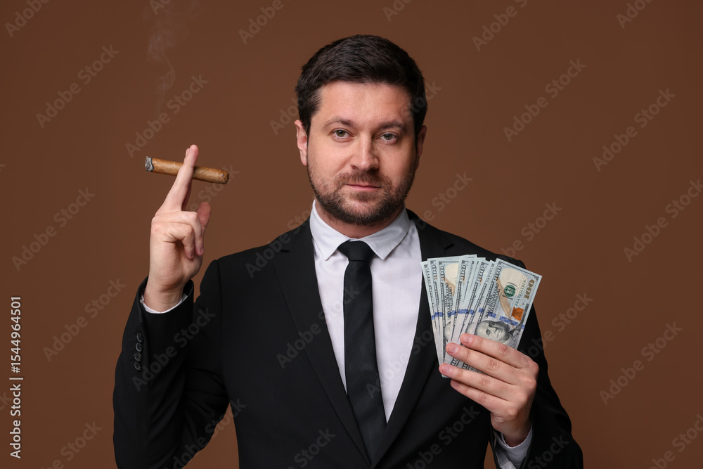 Greedy banker with dollar banknotes smoking cigar on brown background Greedy banker with dollar banknotes smoking cigar on brown background