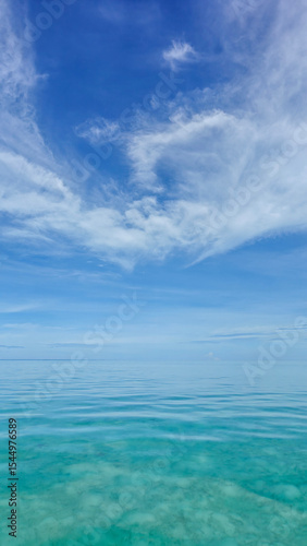 Scenic view of calm and crystal-clear waters in Semporna, Sabah, Malaysia. The vibrant blue sky and pristine ocean reflect the natural beauty of this tropical paradise.