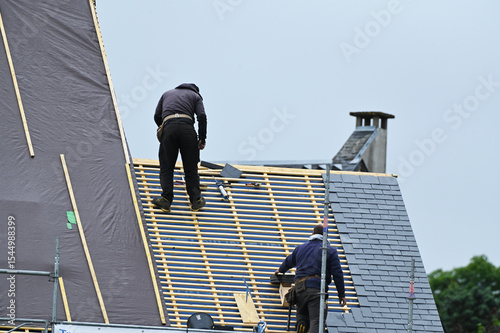ouvrier couvreur sur un toit d'habiation en cours de rénovation