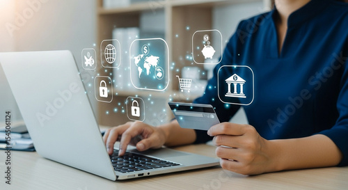 Woman using laptop for online banking with credit card and digital financial icons floating above it