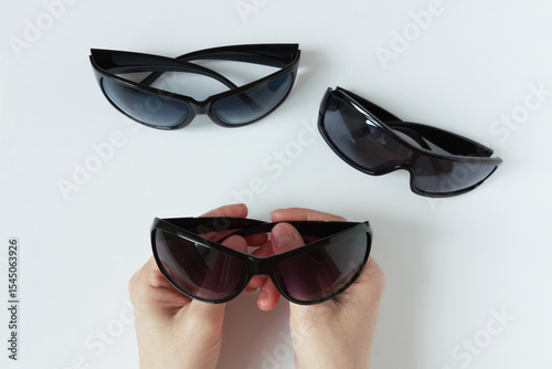 Black framed sunglasses in the hands of a Caucasian woman. The buyer chooses glasses.