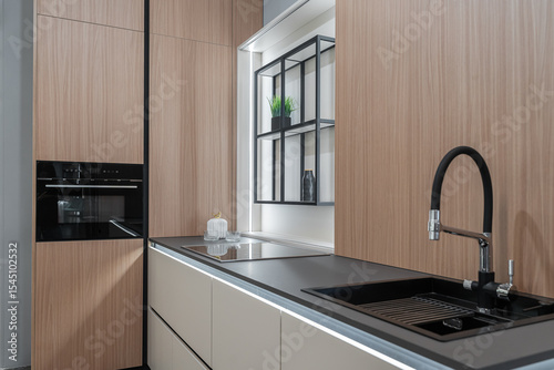 modern  kitchen. built-in kitchen furniture, upper and lower cabinets, built-in appliances. Black faucet and sink. Wooden kitchen. the kitchen is beige and light shades.