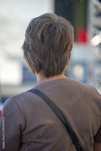 A man with a beard and gray hair is wearing a brown shirt and a black backpack