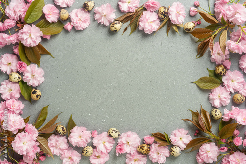 Spring floral frame with pink blossoms and quail eggs on textured background