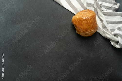 Freshly baked chocolate croissant on striped tablecloth and black surface