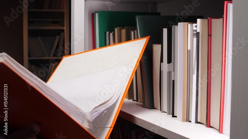 Orange binder opening in a library with bookshelf in background