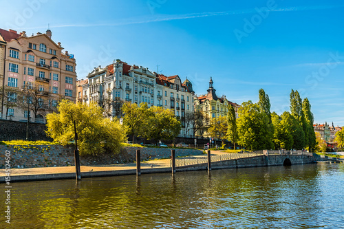 A view from the Vltava river towards colourful buildings on the west bank in Prague in springtime