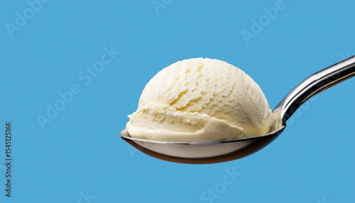 creamy vanilla ice cream scoop on spoon against light blue background