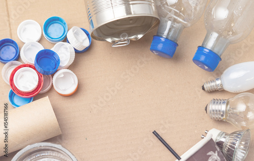 A pile of plastic bottles and cans are scattered on a brown surface. Scene is one of clutter and disorganization