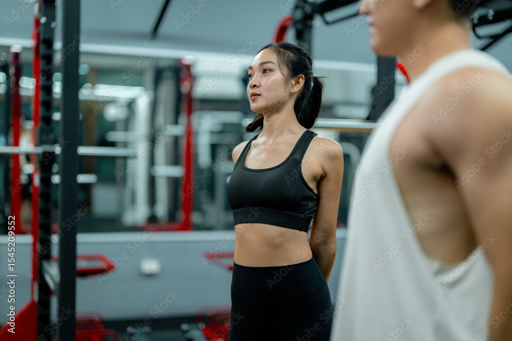 Fototapeta premium Athletic woman stretching back muscles in gym with personal trainer