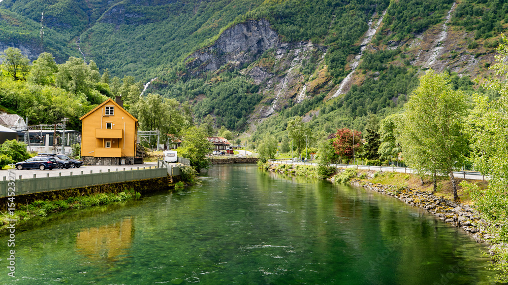 Flam river flowing past traditional Norwegian buildings and mountains Flam river flowing past traditional Norwegian buildings and mountains