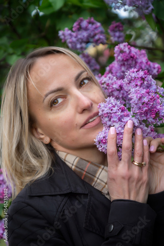 A young, beautiful girl with a beautiful bouquet of lilacs.