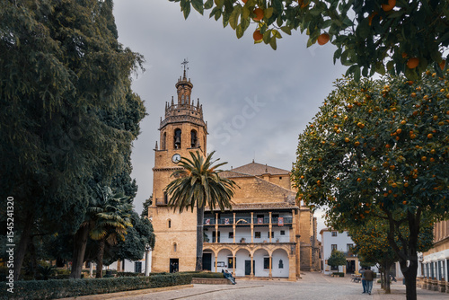 Plaza Duquesa de Parcent, Iglesia de Santa Maria la Mayor and orange trees on cloudy day, Ronda, Spain