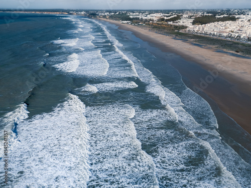 White Spanish town on sea coast wide sand beach big waves, Conil de la Frontera, Andalusia, Spain