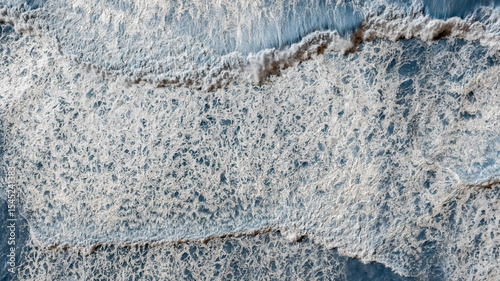 Aerial top down view of sea ​​surf with big waves, white foam on sunny day, Andalusia, Spain
