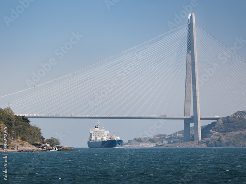 Bosphorus panorama with suspension bridge and heavy loaded cargo ship on sunny day, Istanbul, Turkey