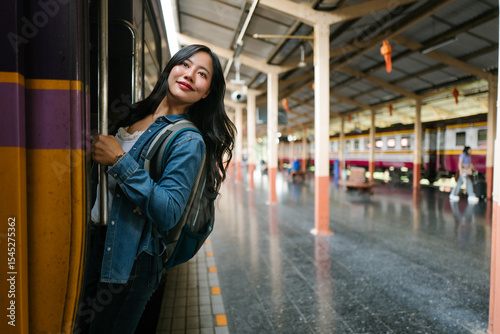 Asian backpacker getting on a train at the platform of the central railway station in Bangkok, Thailand