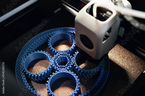 3D printing of a planetary gear set – close-up of FDM printer extruding blue filament for mechanical engineering rapid prototyping and additive manufacturing.