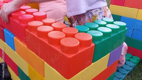 Children build construction sets from colorful plastic pieces at an outdoor playground