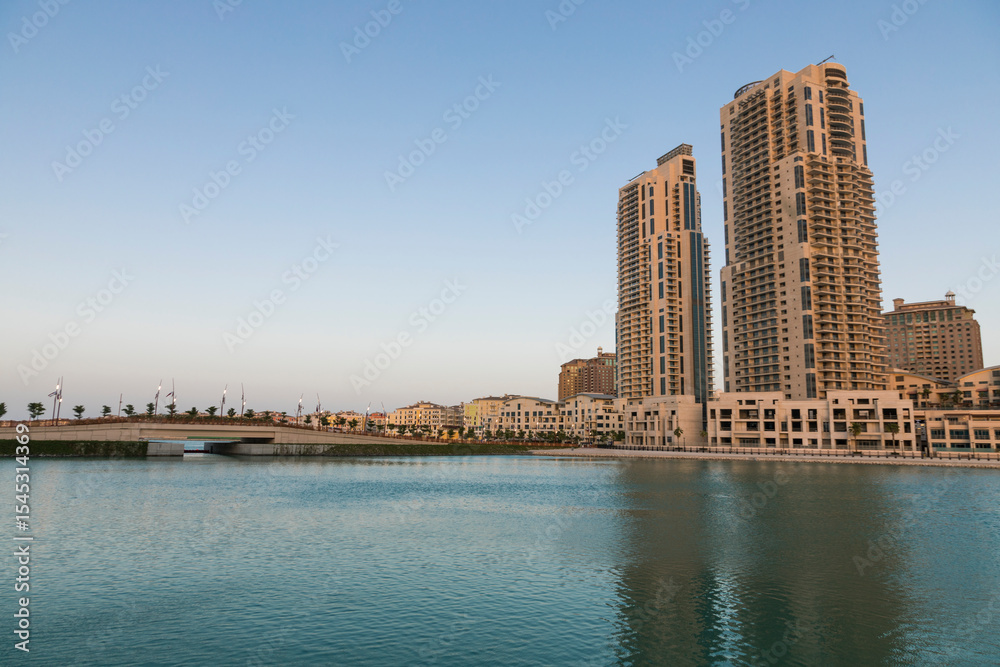 Obraz premium Doha, Qatar - 13 June 2025: A scenic view of vibrant residential buildings along the coast of The Pearl Island in Doha, Qatar the image shows colorful architecture, calm sea water