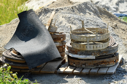 Old rusty manhole covers from drainage shafts, stacked on a building site