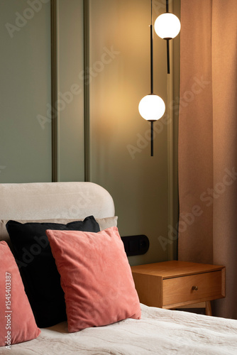 Minimalist bedroom detail with warm pendant lighting, soft neutral bedding, modern bedside table, and elegant contemporary decor in a cozy luxury interior.
