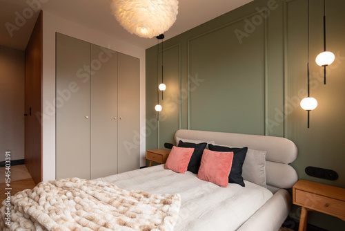 Modern cozy bedroom with soft ambient lighting, sage green accent wall, minimalist decor, upholstered bed, and elegant contemporary interior design in a warm luxury apartment.