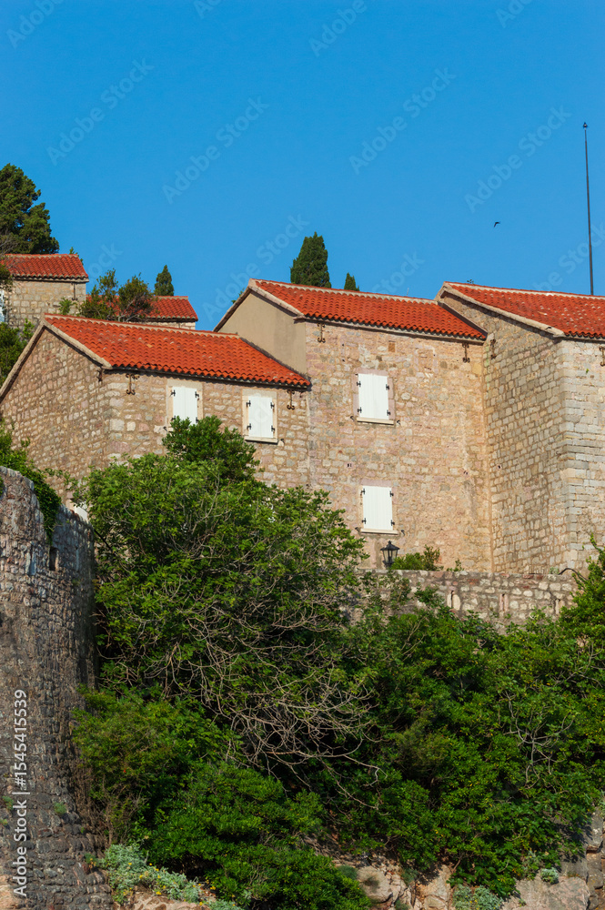 Fototapeta premium A fragment of the stone medieval fortress of Sveti Stefan island-hotel, on the Adriatic coast, Montenegro. Details. Vertical