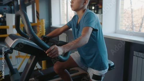 Teenage boy enjoying physical exercise training on mechanical elliptical trainer