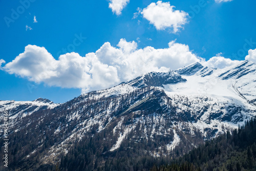 Idyllic landscape in the Alps with fresh green meadows and mountain peaks.