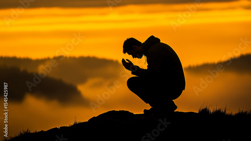 A man kneels in prayer atop a mountain at sunrise, his silhouette framed by golden skies and soft mist below, evoking peace, surrender, and spiritual depth.