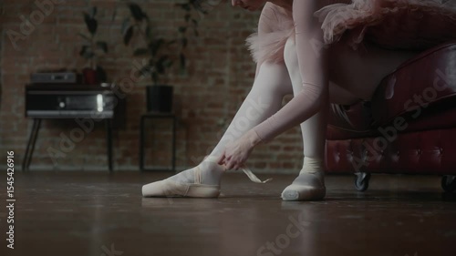 Ballerina is gently and delicately wearing her ballet shoes