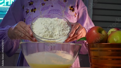 Woman mixing flour into batter for homemade baking in kitchen setting