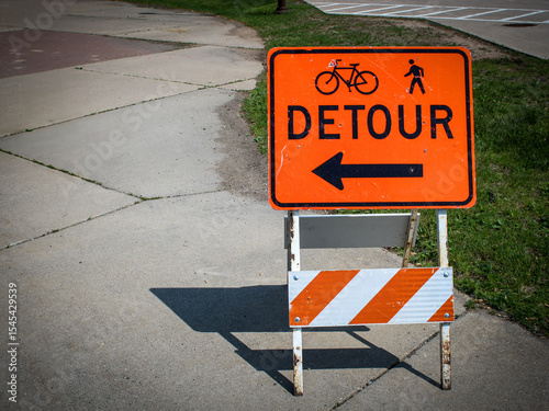 фотографія Close-up of a detour sign on a traffic barricade with an arrow, bicycle, and pedestrian icon with copy space