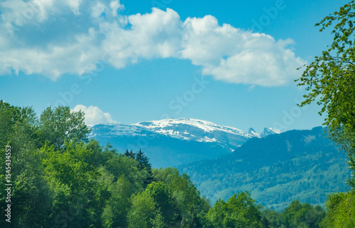 Idyllic landscape in the Alps with fresh green meadows and mountain peaks.