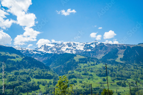 Idyllic landscape in the Alps with fresh green meadows and mountain peaks.