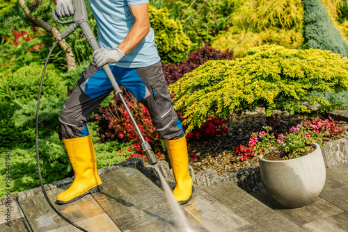 Cleaning Garden Pathways Using a Pressure Washer in Vibrant Landscaped Yard