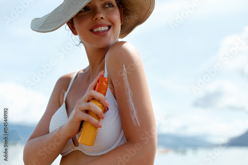 Woman applying sunscreen on tanned skin. Skincare. Body protection sun cream. Bikini woman smears moisturizing lotion on arm. Portrait of a female holding moisturizing sunblock or suntan
