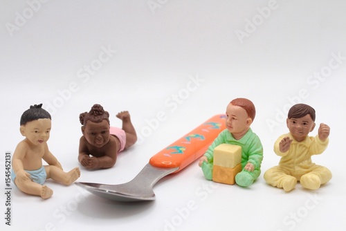 miniature baby figurines next to a weaning spoon