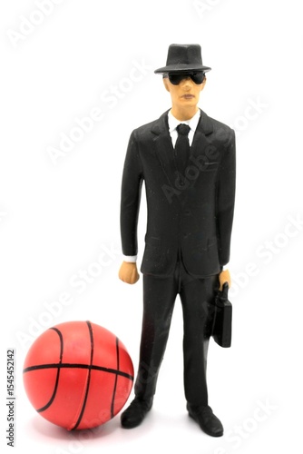 miniature figurine of a manager with briefcase, hat and dark glasses near a basketball
