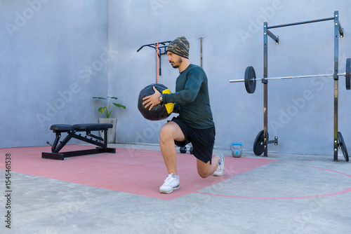 Athlete doing lunges with medicine ball in outdoor gym